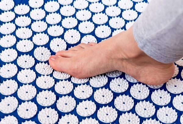 Нога на коврике массажере