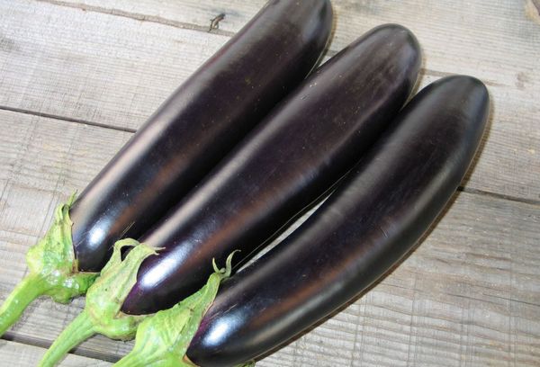 три баклажана на деревянном столе