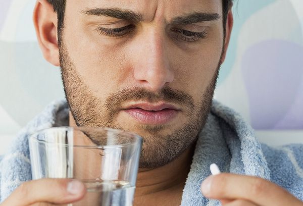 Мужчина пьет таблетку