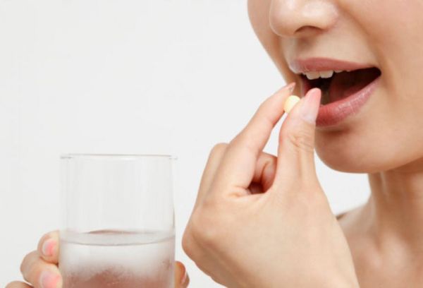 Женщина запивает таблетку