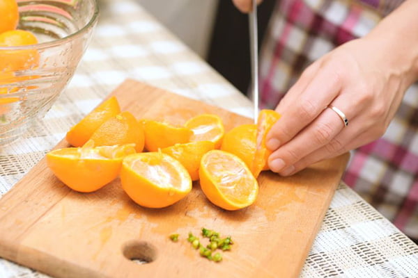 Женщина режет мандарины