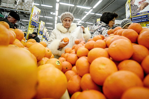 Женщина выбирает мандарины
