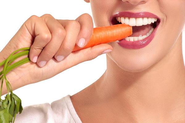 Женщина ест морковь