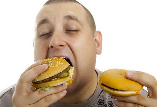 Мужчина ест гамбургеры