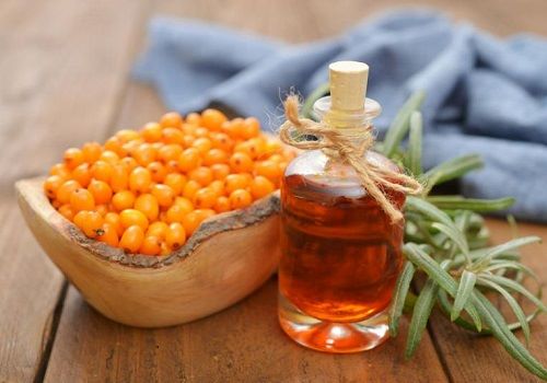 Чашка с облепихой и бутылек с облепиховым маслом