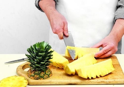 Мужчина разделывает ананас