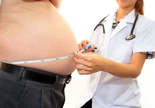 Врач измеряет объем талии у пациента
